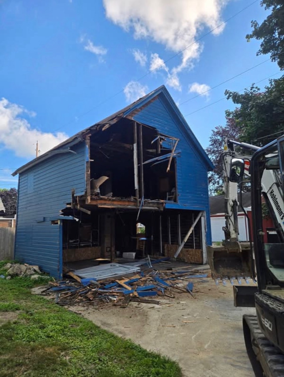 Blue garage partially dismantled with framing exposed during demolition